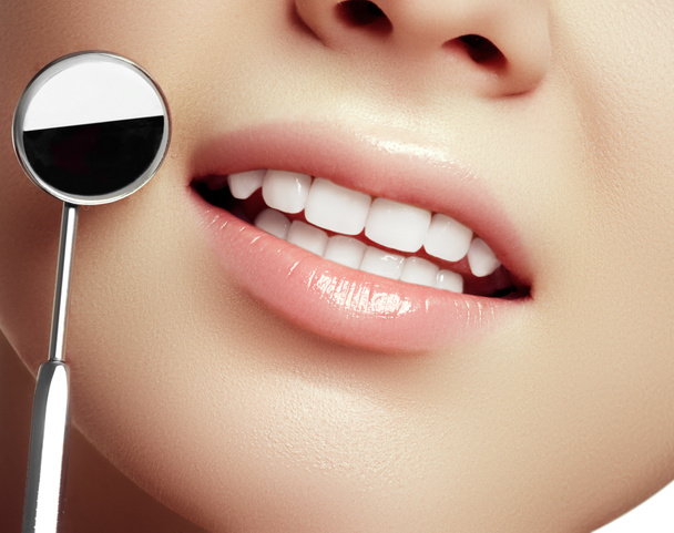 gesunde weiße Frauenzähne und ein Zahnarzt Mundspiegel Nahaufnahme. isoliert auf weißem Hintergrund. Zahnhygiene, Mundpflege-Konzept - Foto, Bild