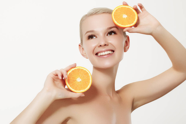 Smiling girl with fresh fruits. Beauty model takes juicy oranges. Joyful girl with freckles. The concept of a healthy diet. Professional make up. Orange slice - Φωτογραφία, εικόνα