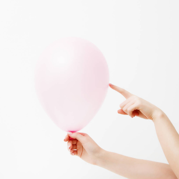 Minimalist fashion and beauty photo. Hand holding a pink balloon on a white wall background with shadow reflection. The concept of St. Valentine's Day or birthday. The 14th of February - Fotó, kép