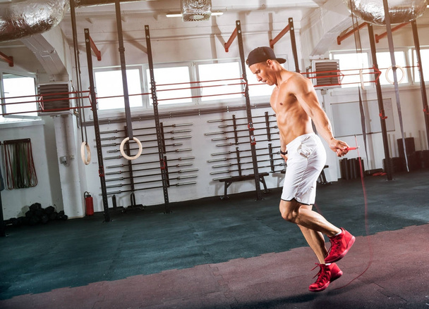 Uomo muscolare che salta l'esercizio con corda da salto in palestra
 - Foto, immagini