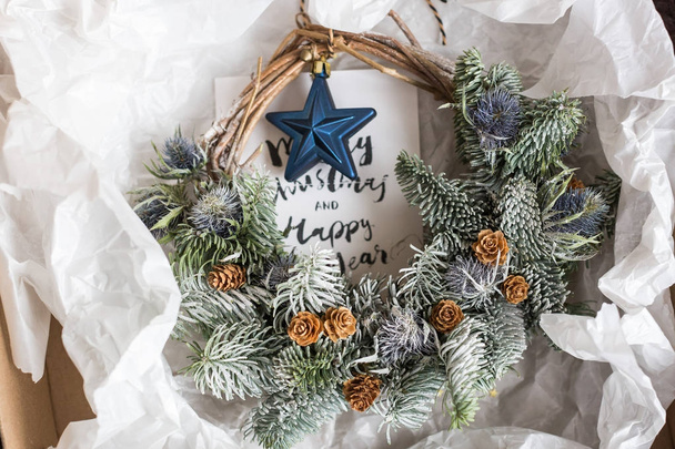 regalos, interior, concepto de artesanía. en el papel de regalo blanco hay una corona maravillosa para decorar el espacio para la Navidad y la tarjeta de felicitación con letras caligráficas
 - Foto, imagen