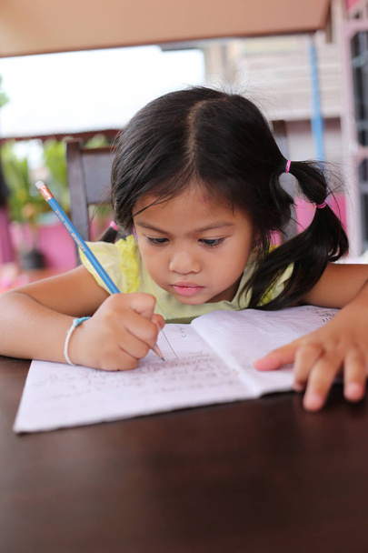 Азіатський дитини дівчина використовувати олівець писати листи на книгу в концепції освіти і навчання. - Фото, зображення