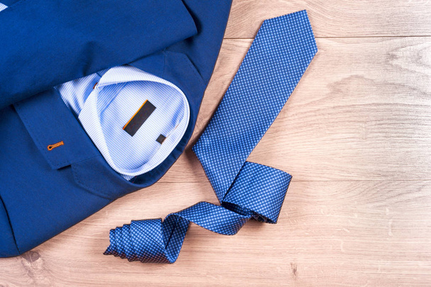 ensemble de vêtements classiques pour hommes costume bleu, chemises, chaussures brunes, ceinture et cravate sur fond en bois. - Photo, image