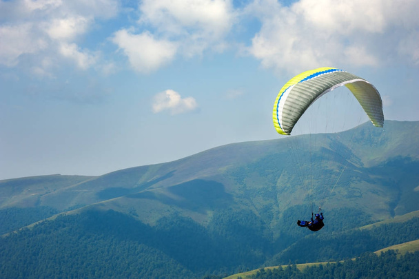Paraglider flies over a mountain valley on a sunny summer day.  - Photo, Image