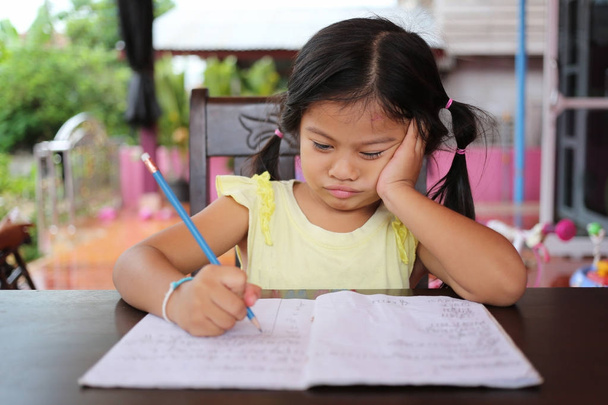 Азиатская девочка использует карандаш писать письма на книге в концепции образования и обучения
. - Фото, изображение