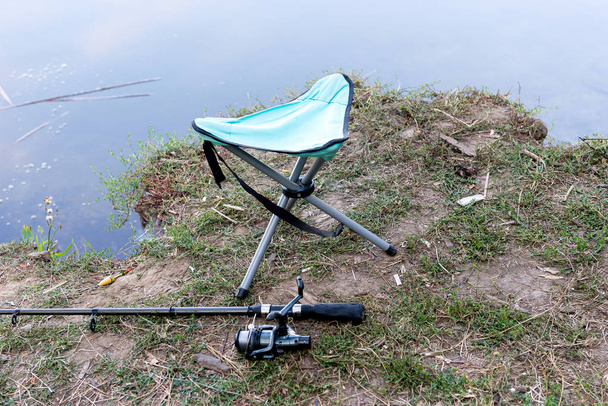 Fishing rod, folding stool, float and other gear on the river bank. - Photo, Image