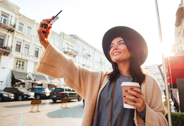 Portrait of a cheery pretty woman taking a selfie - Photo, Image