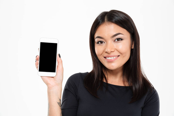 Cheerful young asian woman showing display of mobile phone - Fotó, kép