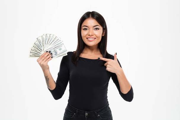 Asian woman standing isolated holding money pointing. - Valokuva, kuva