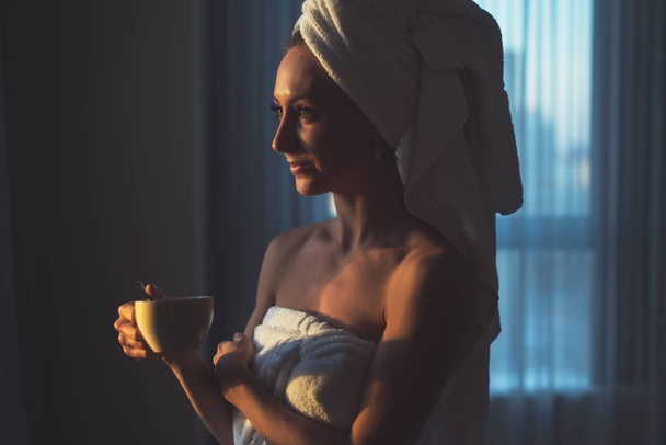 Donna nuda con asciugamano sulla testa e il corpo bere tisana dopo il bagno
. - Foto, immagini