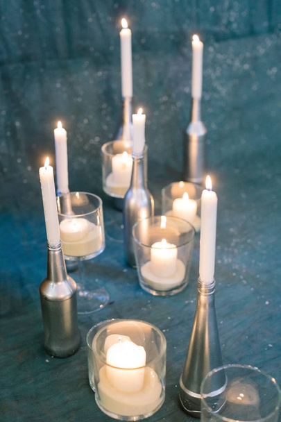 illumination, romance, handmade concept. path created of many burning candles, their holders have different shapes and sizes, they made of old bottles covered silver paint - Photo, Image