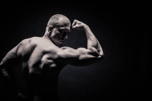 portrait of a male bodybuilder, straining muscles in sports pose - Foto, Imagen