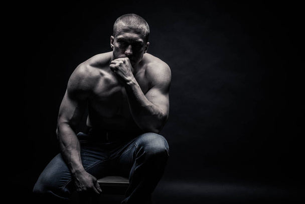 portrait of a seated male bodybuilder, on a black background iso - Foto, afbeelding