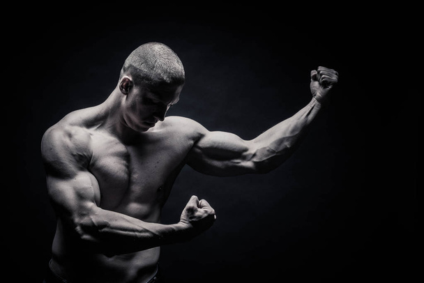 portrait of a male bodybuilder, straining muscles in sports pose - Фото, изображение