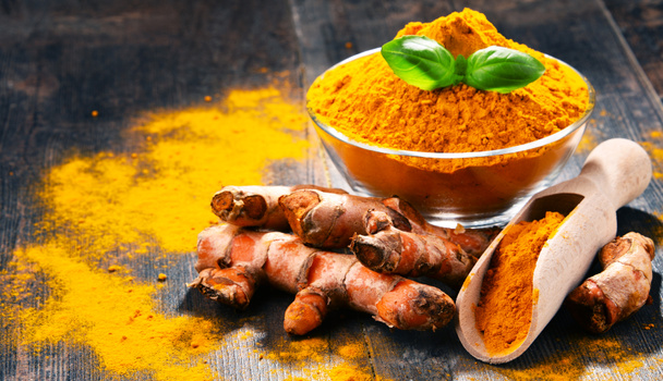 Composition with bowl of turmeric powder on wooden table - Photo, Image