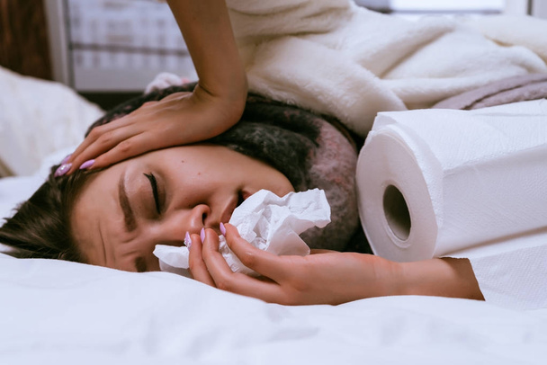 the girl fell ill because of the cold winter weather, sneezes, sore throat, lies on the bed all day - Foto, Imagem