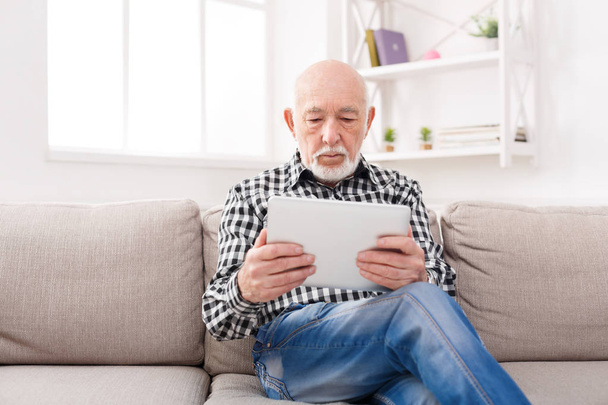 Senior liest Nachrichten auf digitalem Tablet - Foto, Bild