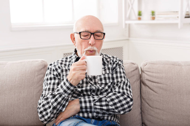 リビング ルームでのコーヒーのカップを持っている年配の男性 - 写真・画像