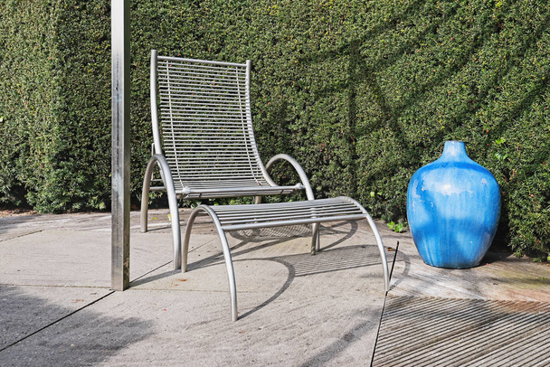 Cadeira de jardim moderno com banco de pés e vaso azul decorativo com
 - Foto, Imagem