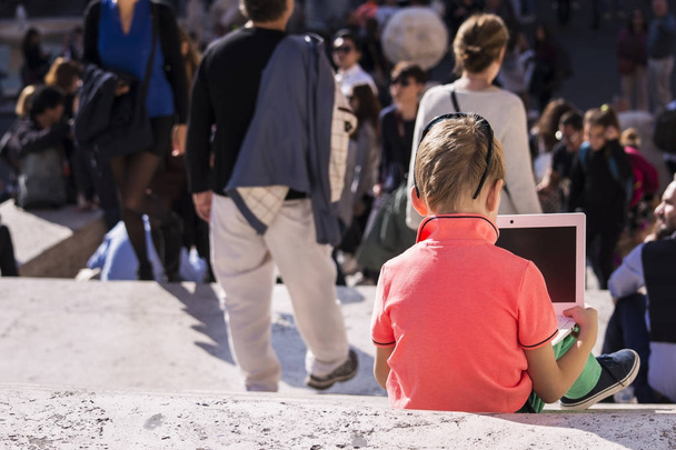 boy looks at a laptop on the steps and a lot of people - Fotoğraf, Görsel