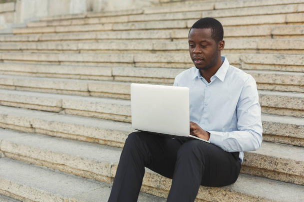 Afrikkalais-amerikkalainen liikemies työskentelee kannettavan tietokoneen kanssa ulkona
 - Valokuva, kuva