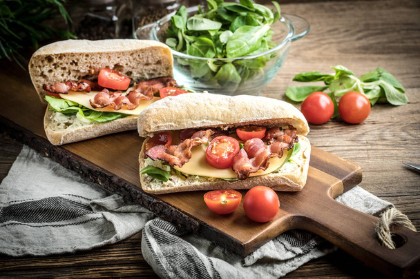 Ciabatta sandwich with arugula salad, bacon and yellow cheese. - Zdjęcie, obraz