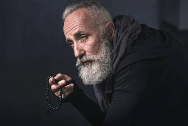 Thoughtful old man holding beads in arm - Valokuva, kuva