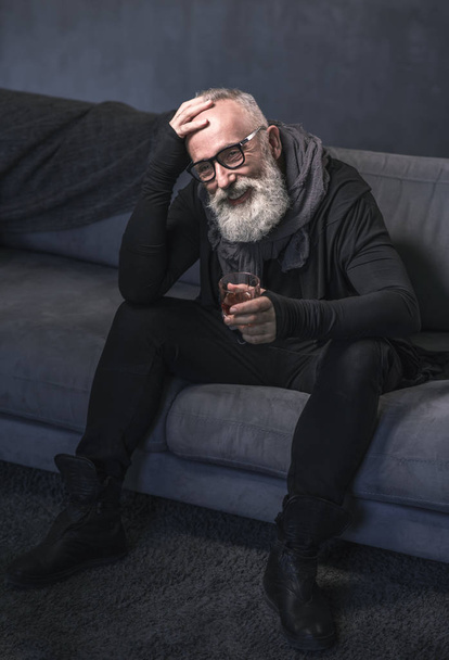 Happy old man drinking whisky on sofa - Фото, зображення