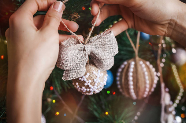 Hipster hands with Christmas sackcloth ball and bow - Φωτογραφία, εικόνα