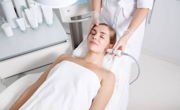 Pretty girl having ultrasound facial procedure at beauty salon - Foto, afbeelding