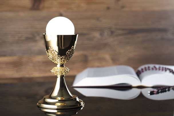 カトリックの宗教テーマ。聖書、ロザリオ、木製の背景に黄金の杯. - 写真・画像