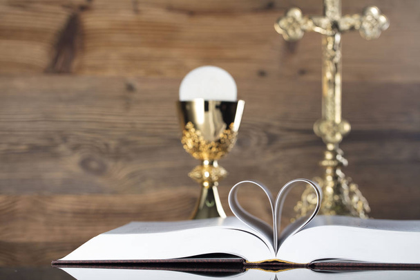 Тема католицької релігії. Хрест, Священну Біблію та золоту чашу на фоні дерев'яні. - Фото, зображення