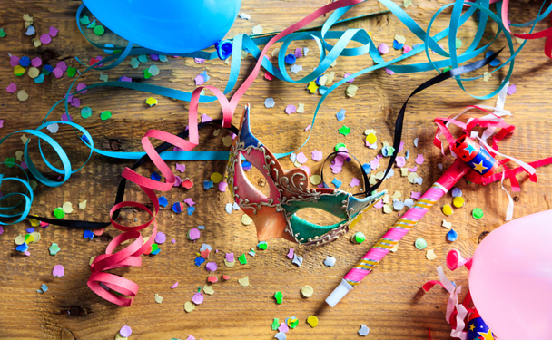 Carnival party. Mask, confetti and serpentines on wooden floor - Photo, Image