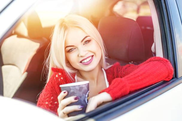 Молодая женщина пьет кофе в машине утром. Смех
. - Фото, изображение