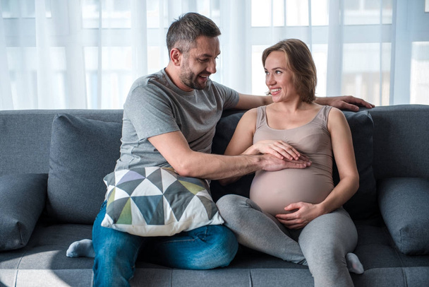 Cheerful married couple touching pregnant belly - Valokuva, kuva