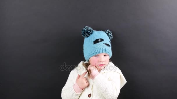 Klein meisje is gekleed in winter kleding. Schattig klein meisje op zwarte achtergrond. - Video