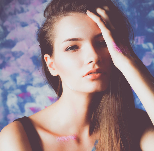 Young beautiful woman sitting near painting wall - 写真・画像