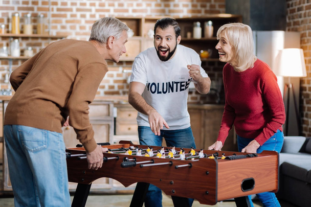 Emotional people of different age playing table football together - Photo, Image