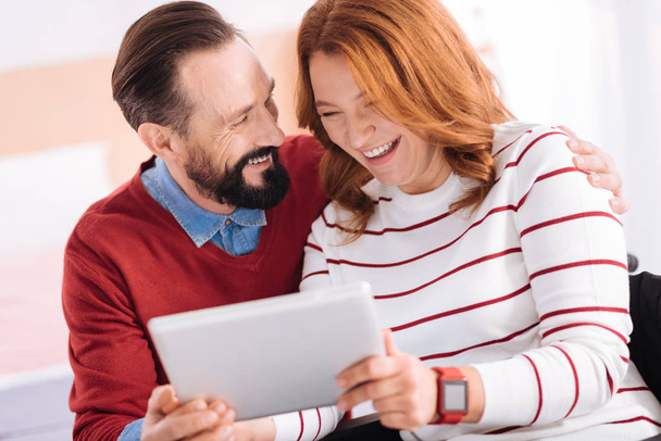 man and woman laughing while using a tablet - Foto, afbeelding