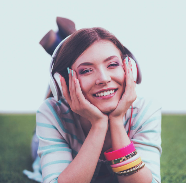 Woman listening to the music lying on green grass - Photo, Image