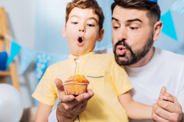 Upbeat son and father blowing out candle  - Photo, image