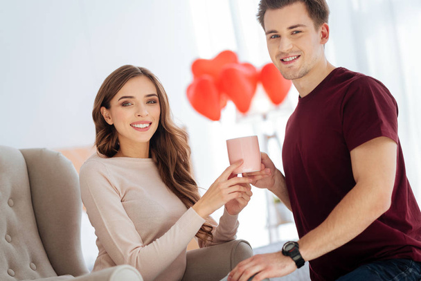 Beaming couple smiling while warming up with aromatic tea - Zdjęcie, obraz