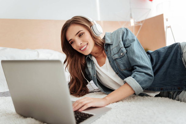 Cheerful girl smiling while working on laptop - Фото, изображение