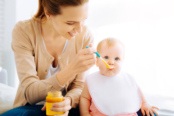 Pleasant young woman feeding a cute baby - Foto, Imagen