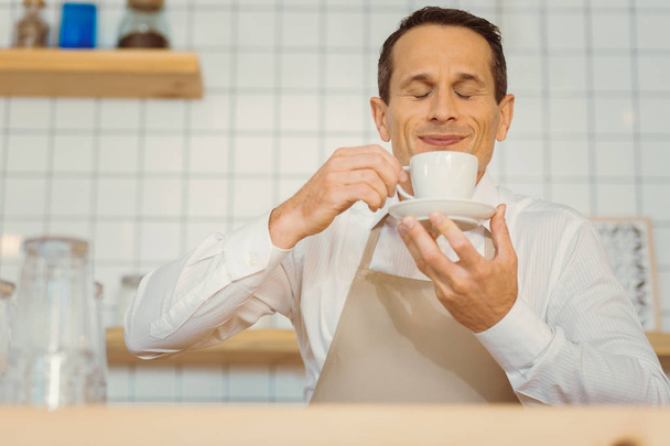 Nice positive man smelling the coffee - Фото, изображение