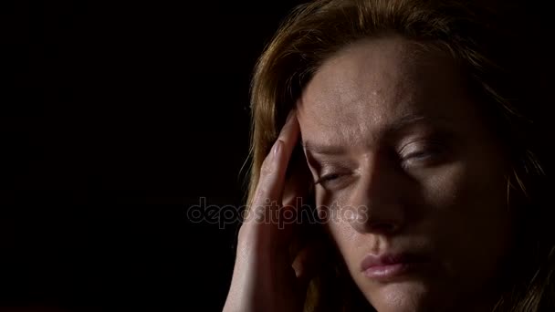 primer plano, mujer triste con un dolor de cabeza sobre un fondo oscuro. 4k, cámara lenta
 - Metraje, vídeo