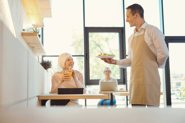 Positive elderly woman looking at the waiter - Foto, Imagen
