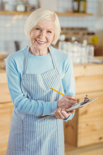 Positive elderly woman wearing an apron - Фото, зображення