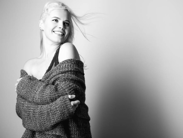 Young blond sensual model in a knitted sweater pose in studio. Black-white photo. - 写真・画像