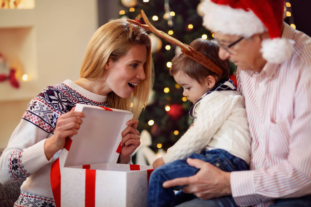 sharing gift on Christmas- smiling mother giving present to son - Foto, Imagem